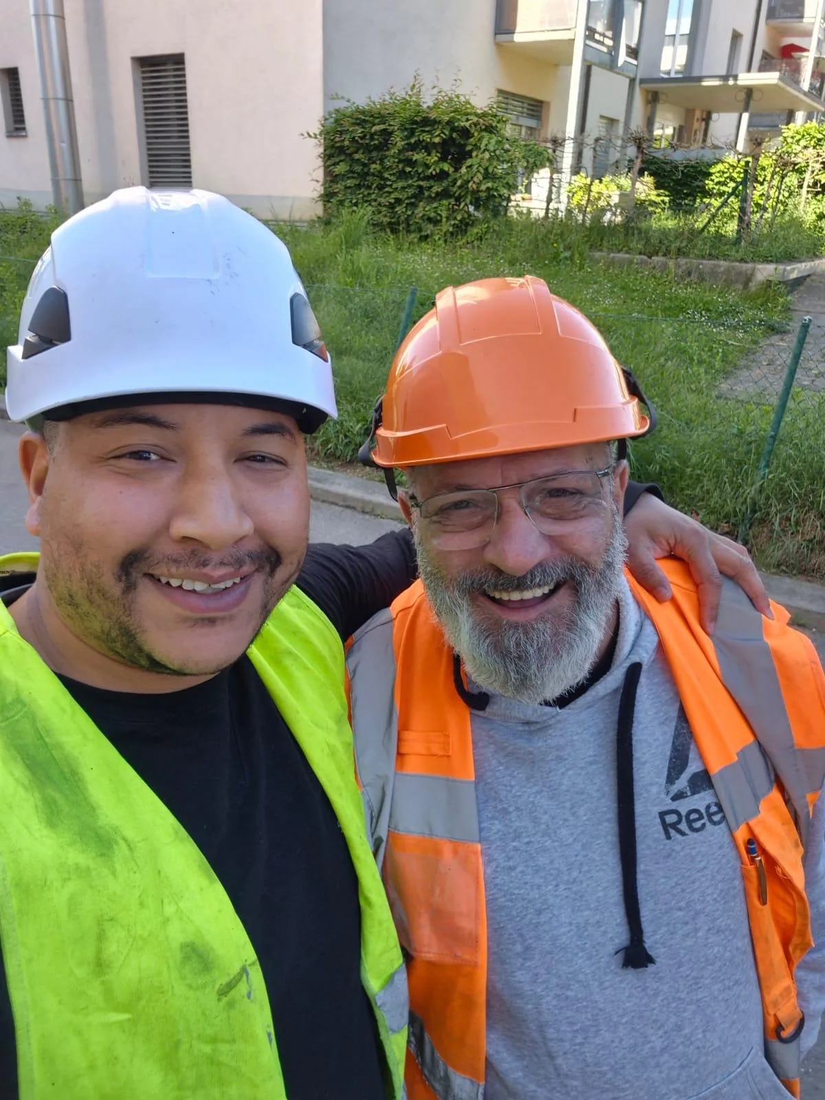 Abdel Lagragui et Serge, souriants en équipement de protection sur un chantier